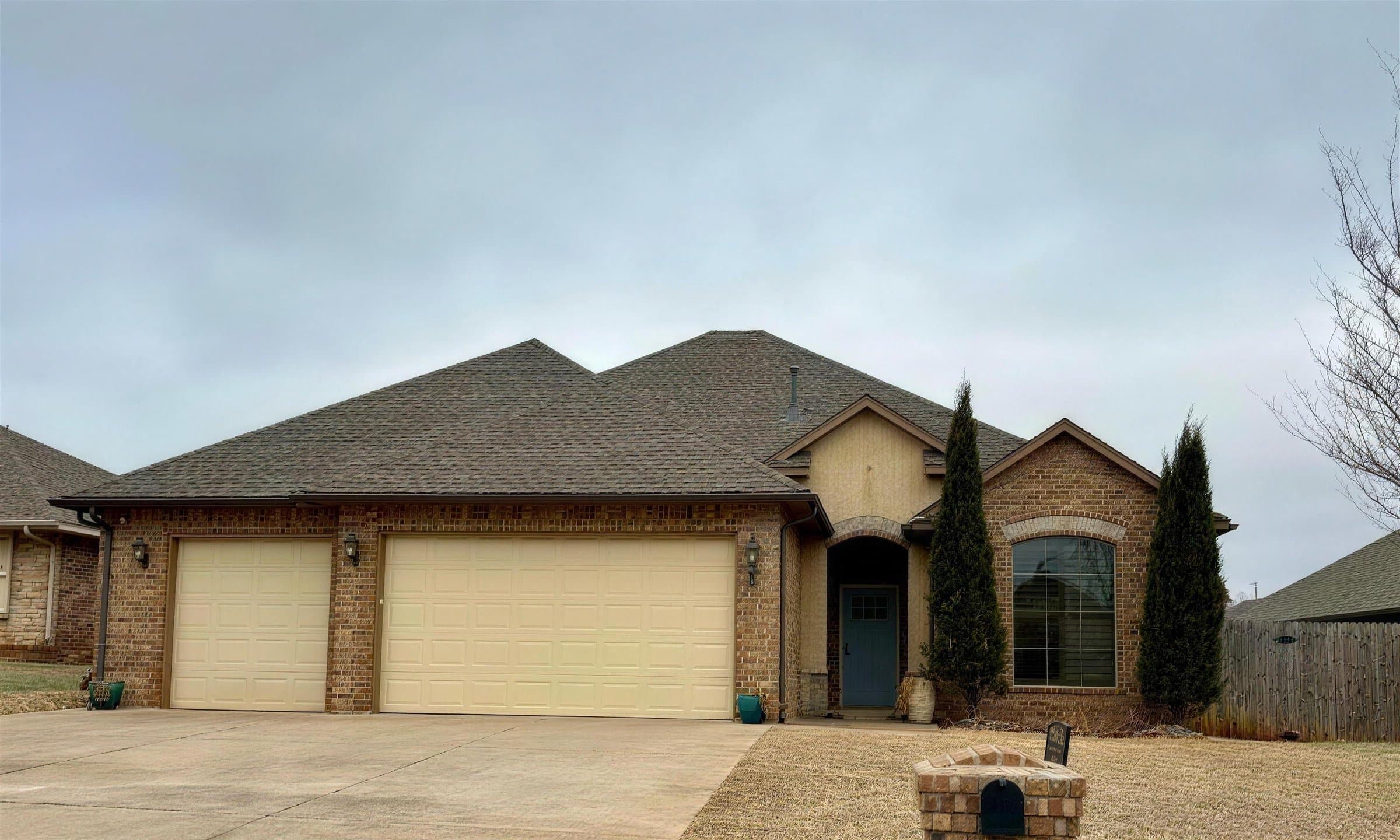 Brick home with a new brown shingle roof and a two car garage